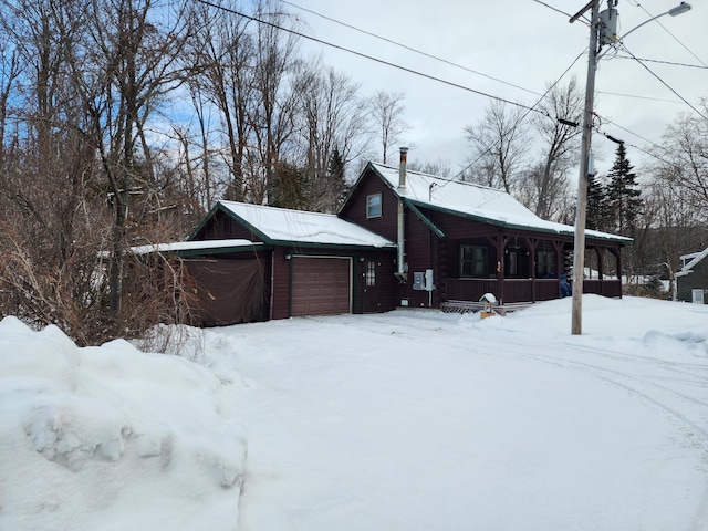 view of snowy exterior with a garage and covered porch