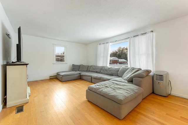 living room with light hardwood / wood-style floors, a textured ceiling, and a baseboard heating unit