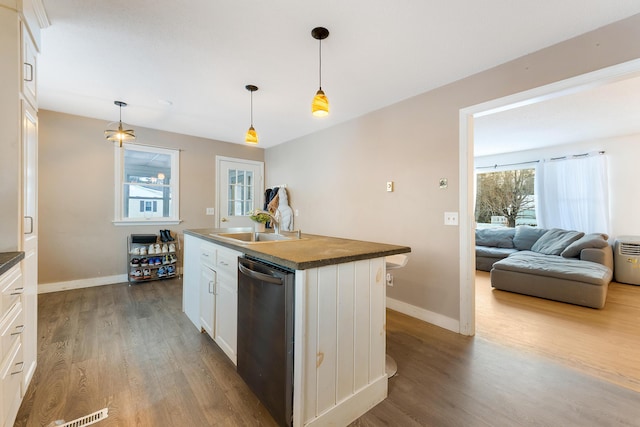 kitchen featuring pendant lighting, white cabinetry, an island with sink, sink, and stainless steel dishwasher