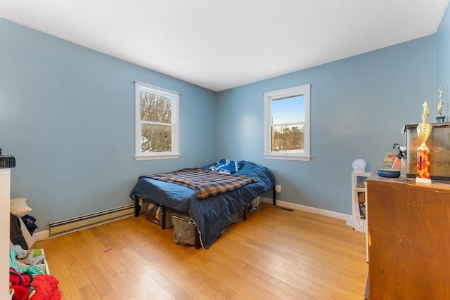 bedroom featuring a baseboard heating unit and light hardwood / wood-style flooring