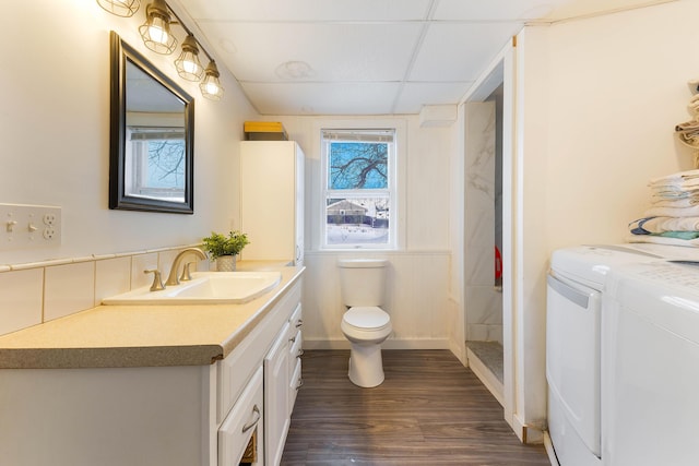 bathroom featuring hardwood / wood-style flooring, washer and clothes dryer, a paneled ceiling, vanity, and toilet