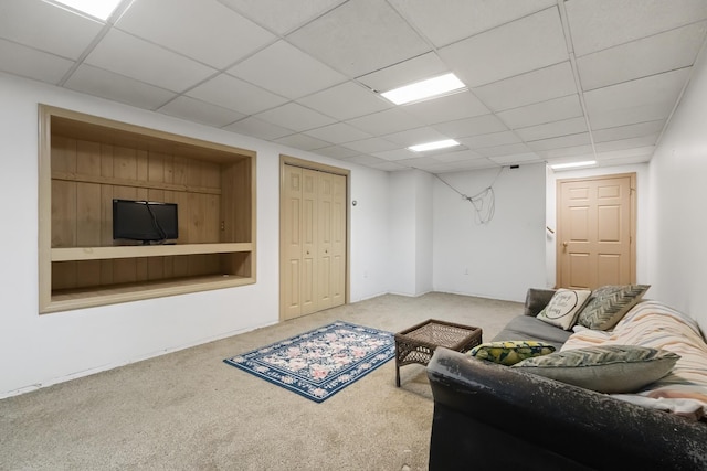 living room with a drop ceiling and carpet