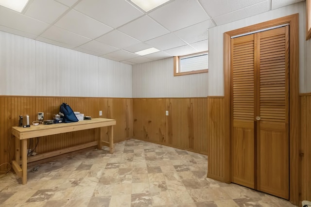 office area featuring wood walls and a drop ceiling