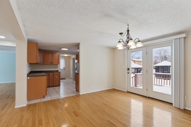 kitchen with hanging light fixtures, a healthy amount of sunlight, a notable chandelier, and light hardwood / wood-style flooring