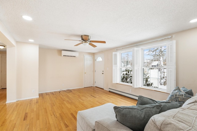 living room featuring a baseboard radiator, a wall mounted AC, a textured ceiling, and light hardwood / wood-style floors