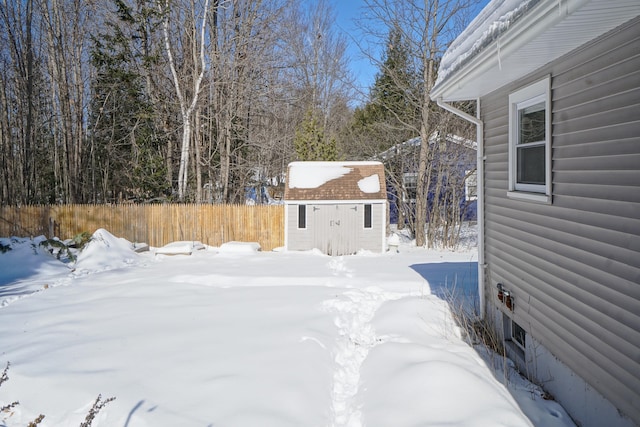 snowy yard with an outbuilding, fence, and a storage unit