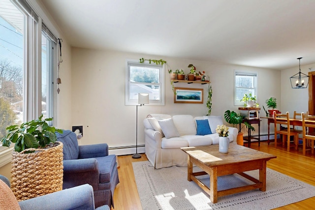 living area with light wood-style floors, a baseboard heating unit, and a chandelier