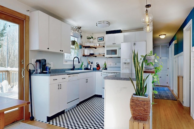 kitchen featuring hanging light fixtures, white appliances, white cabinetry, and a sink