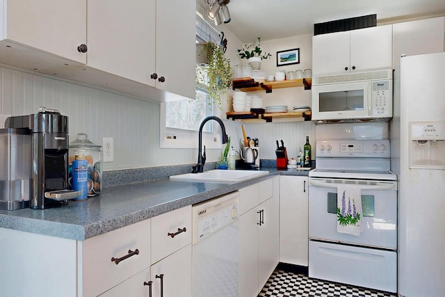 kitchen with white appliances, white cabinetry, a sink, and tile patterned floors