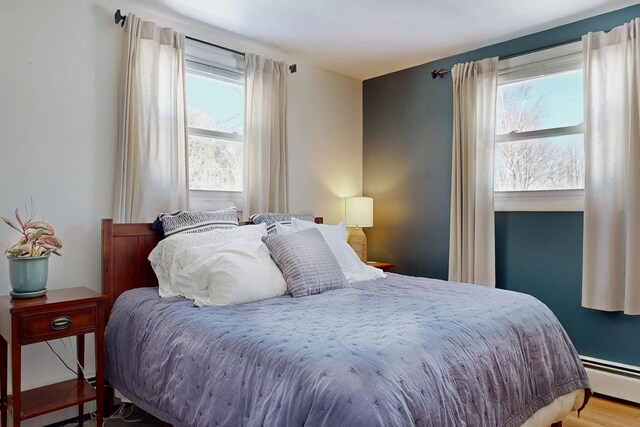 bedroom with a baseboard heating unit and wood finished floors