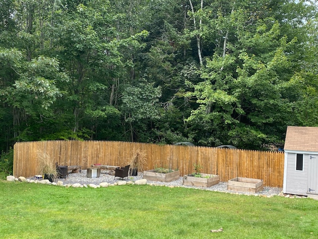 view of yard with a garden, fence, an outdoor structure, and a storage unit