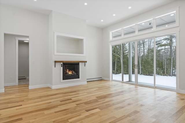 unfurnished living room featuring light wood-type flooring and a baseboard heating unit