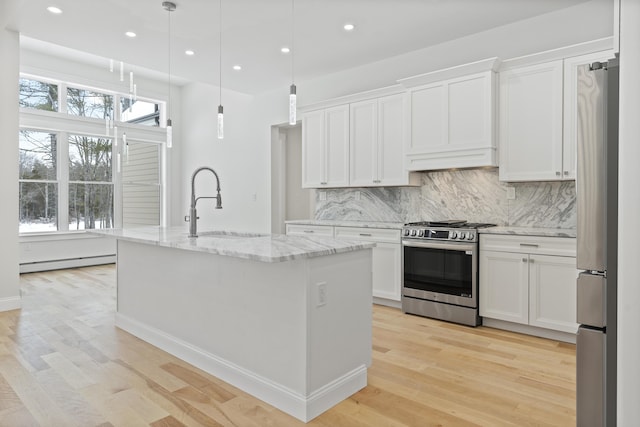 kitchen with sink, a center island with sink, appliances with stainless steel finishes, pendant lighting, and white cabinets