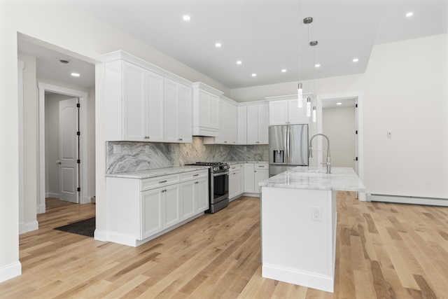 kitchen with light stone counters, hanging light fixtures, a center island with sink, stainless steel appliances, and white cabinets