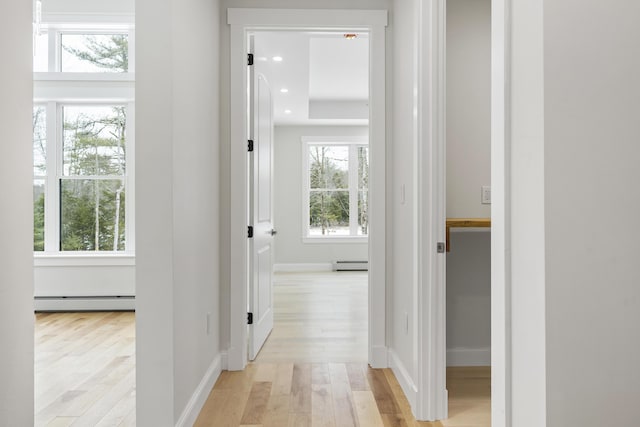 corridor featuring light wood-type flooring and a baseboard heating unit