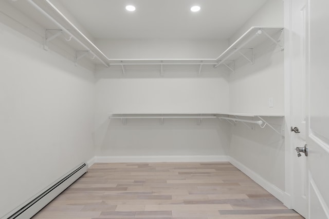 spacious closet with light hardwood / wood-style floors and baseboard heating