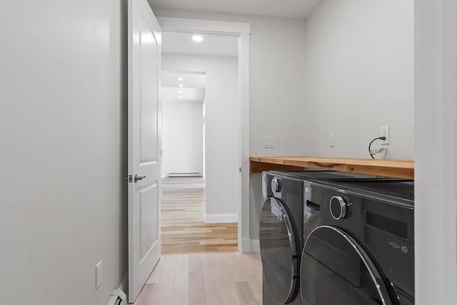 laundry area featuring a baseboard heating unit, washing machine and clothes dryer, and light wood-type flooring