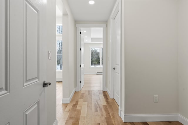 hall with light hardwood / wood-style floors and a baseboard heating unit