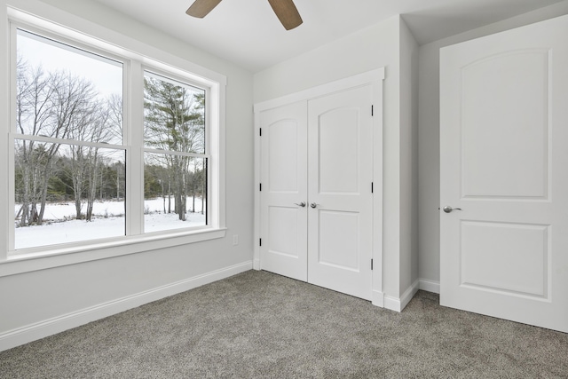 unfurnished bedroom featuring ceiling fan, dark carpet, and a closet