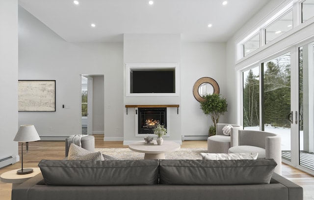 living room with a baseboard heating unit and light wood-type flooring