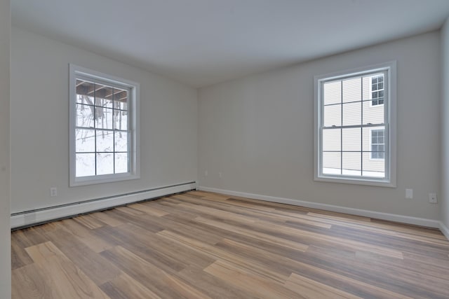 spare room with light wood-type flooring and a baseboard heating unit