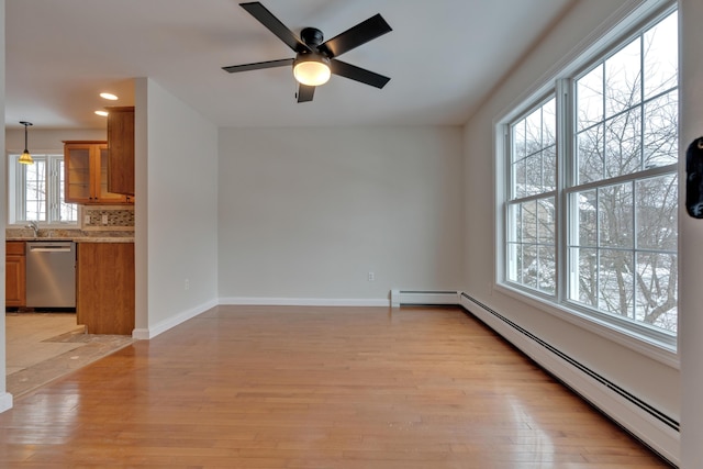 spare room with baseboard heating, ceiling fan, sink, and light hardwood / wood-style floors