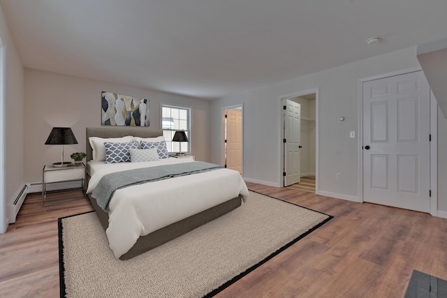 bedroom featuring hardwood / wood-style flooring, a walk in closet, and baseboard heating