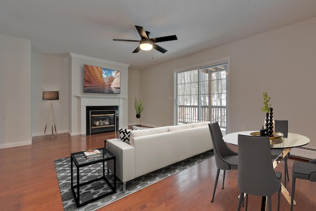 living room featuring wood-type flooring, a baseboard radiator, and ceiling fan