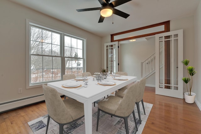 dining space with french doors, ceiling fan, baseboard heating, and light hardwood / wood-style floors