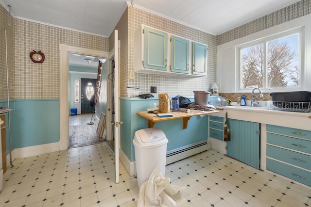 kitchen featuring ornamental molding, baseboard heating, wainscoting, light floors, and wallpapered walls