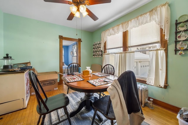 dining space featuring baseboards, wood-type flooring, a ceiling fan, and radiator