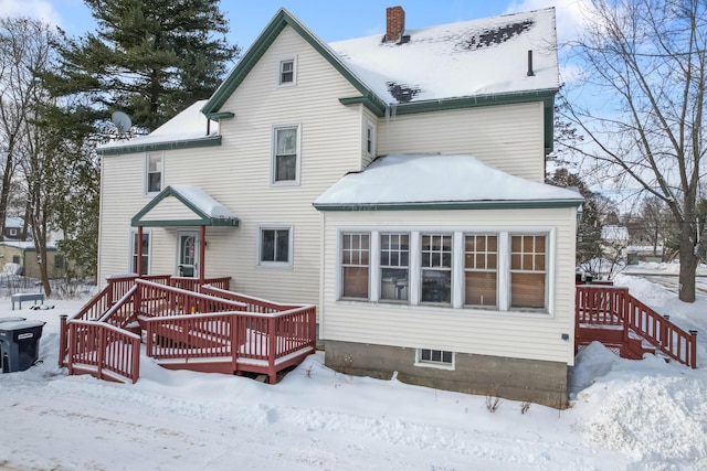 snow covered back of property featuring a chimney and a deck