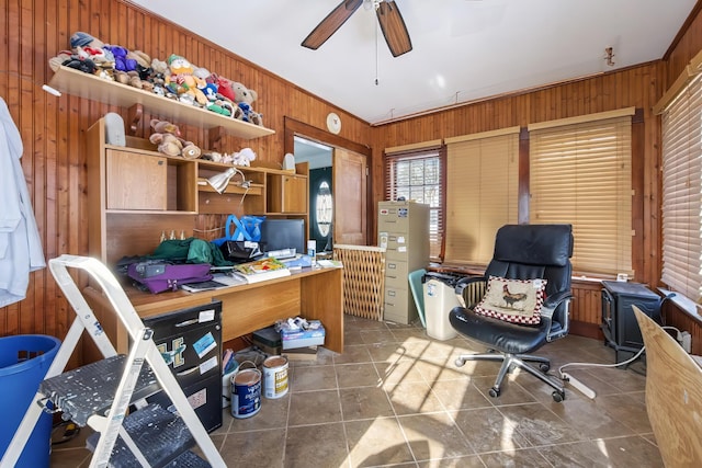 tiled home office featuring a ceiling fan and wood walls