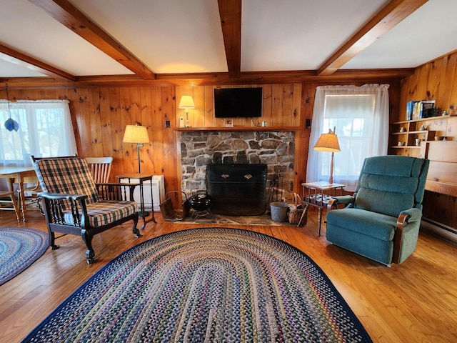 living room with beamed ceiling, a stone fireplace, hardwood / wood-style floors, and wood walls