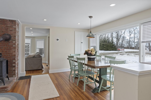 dining room with plenty of natural light, a wood stove, and dark hardwood / wood-style floors