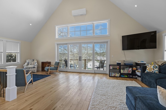 living room with light hardwood / wood-style flooring, a wall unit AC, french doors, and a healthy amount of sunlight