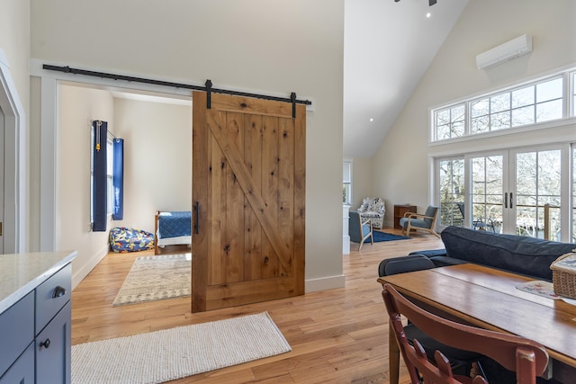 living room with french doors, a barn door, high vaulted ceiling, and light hardwood / wood-style flooring