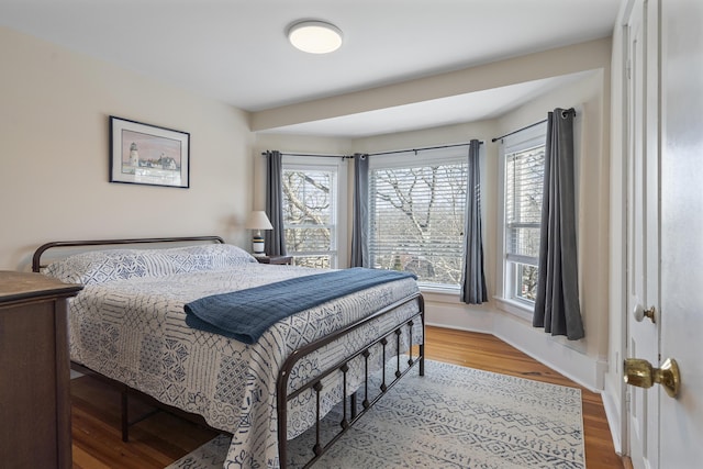 bedroom with multiple windows and hardwood / wood-style flooring