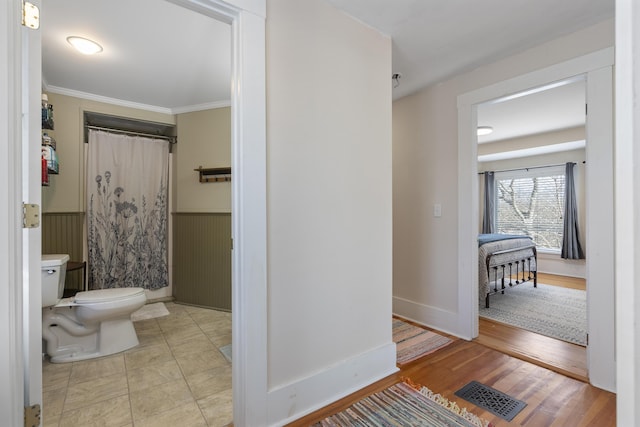 bathroom with crown molding, hardwood / wood-style floors, a shower with shower curtain, and toilet