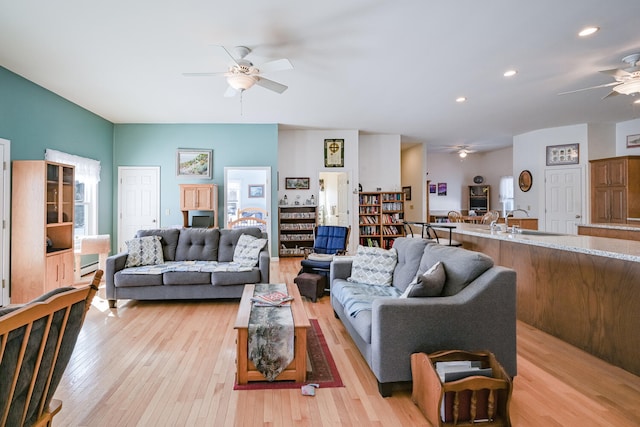 living room featuring sink, a baseboard radiator, ceiling fan, and light hardwood / wood-style flooring