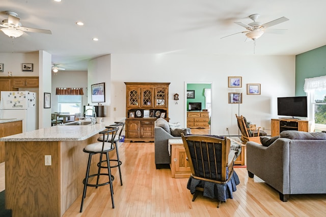 living room with ceiling fan, sink, and light hardwood / wood-style floors