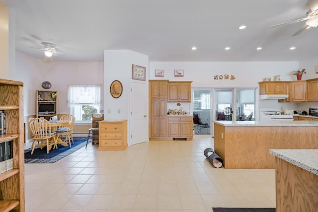 kitchen with light stone counters, light tile patterned flooring, ceiling fan, light brown cabinetry, and white gas range