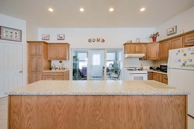 kitchen featuring white appliances, a center island, and light stone counters