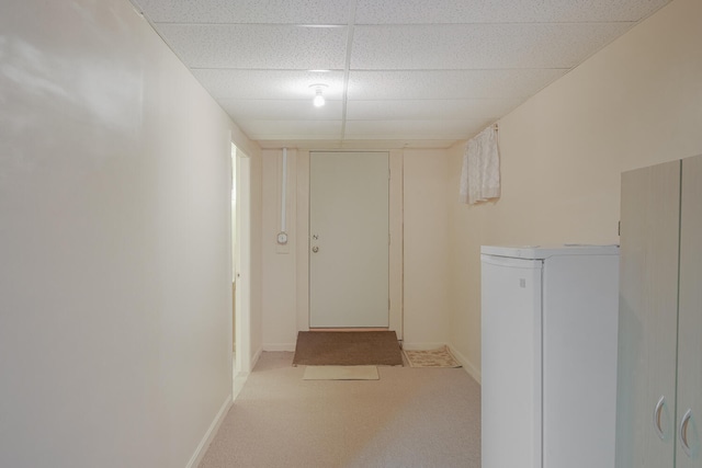 corridor featuring a paneled ceiling and light colored carpet