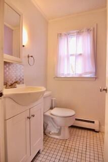 bathroom featuring baseboard heating, ornamental molding, vanity, and toilet