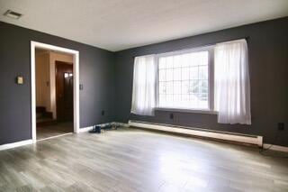 empty room featuring hardwood / wood-style flooring and a baseboard radiator