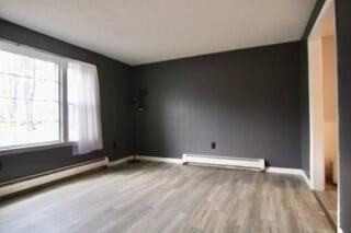 spare room with a baseboard heating unit and light hardwood / wood-style flooring