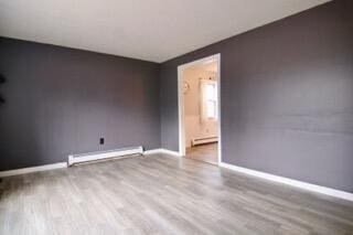 empty room featuring light hardwood / wood-style flooring and a baseboard heating unit