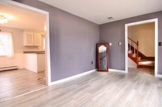 unfurnished living room with a baseboard radiator and light wood-type flooring