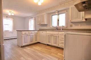 kitchen featuring paneled built in fridge, kitchen peninsula, extractor fan, and a wealth of natural light